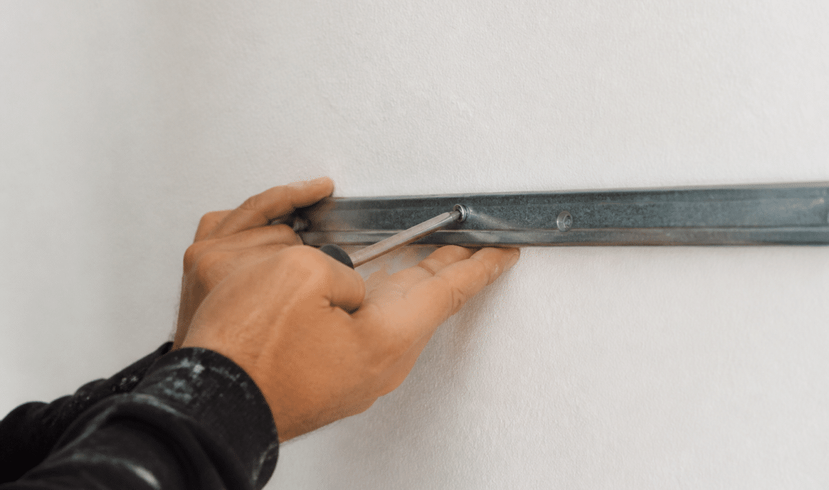 Mains vissant support metal horizontal sur mur blanc