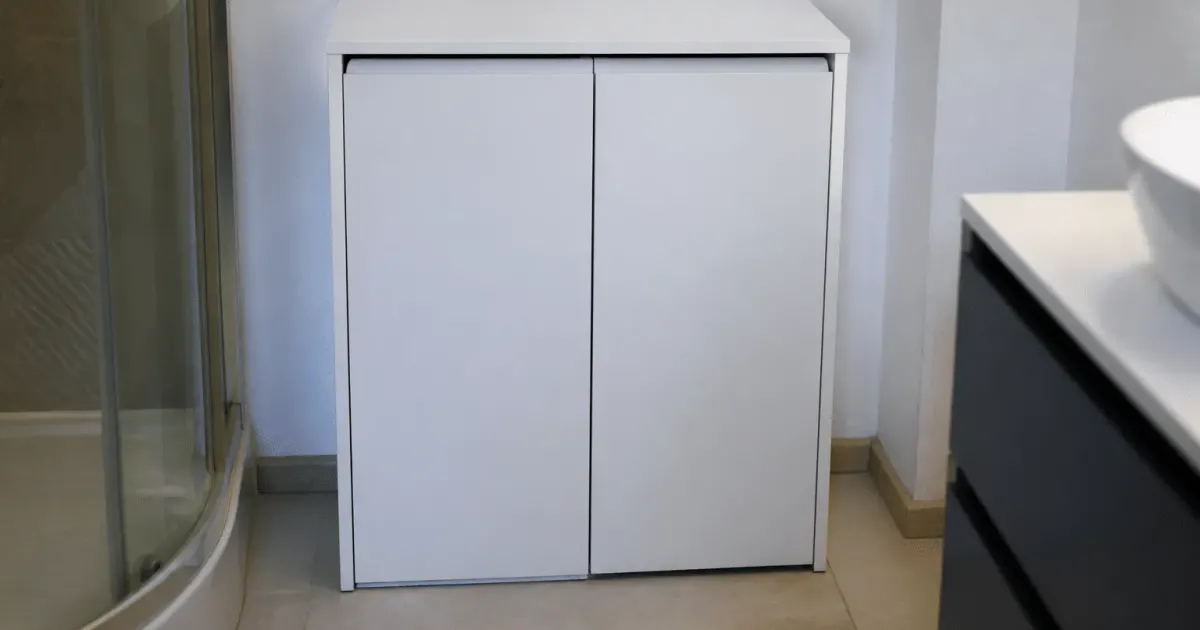 Petit meuble blanc avec portes fermees contre mur salle bain