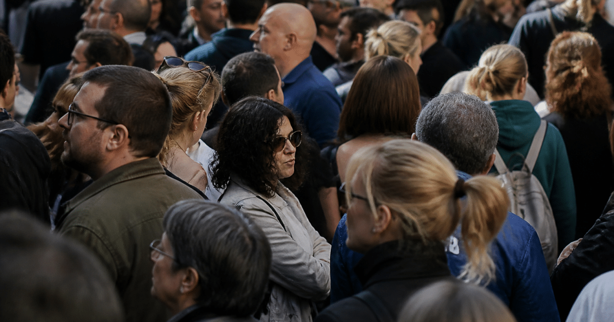 Foule dense de personnes debout cote a cote dans rue urbaine