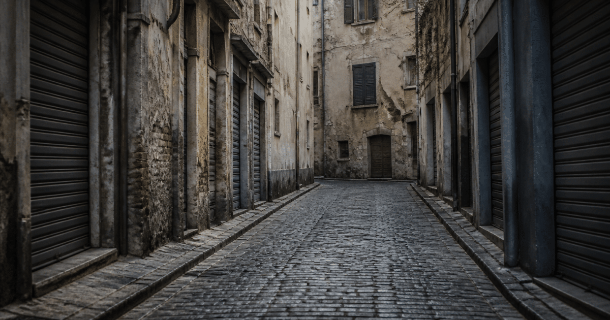 Rue pavée sombre avec bâtiments délabidés fermés volets baissés